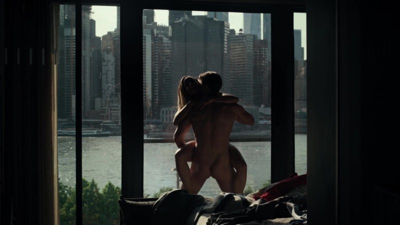 Naked woman stands by the window