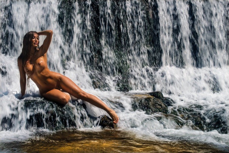 Naked women under a waterfall