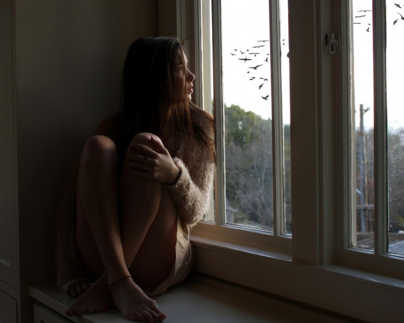 The girl undresses in the window