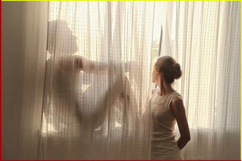 The woman looks out the window