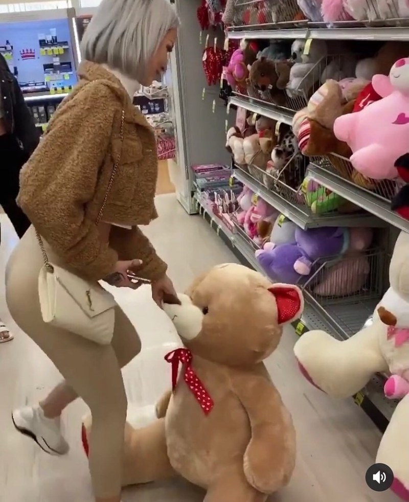 Girl on a plush bear in a store
