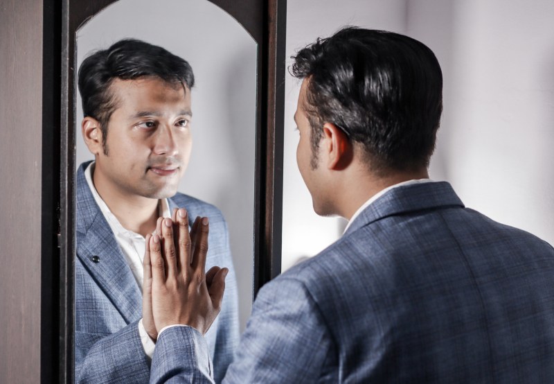 A man in a suit looks in the mirror