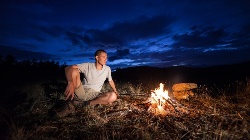 The guy sits by the fire