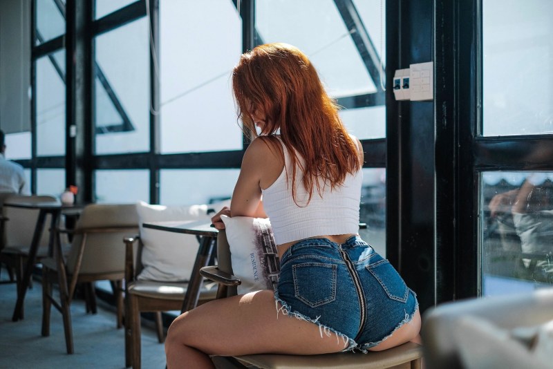 Red -haired girl in jeans shorts
