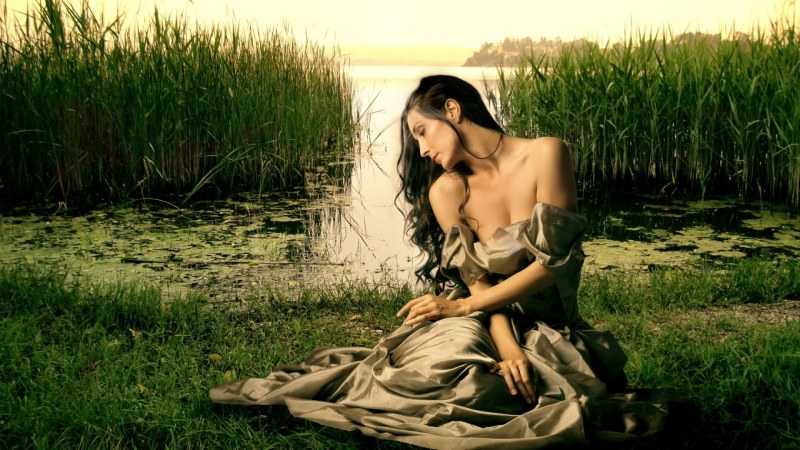Girl sits on the grass in a long dress