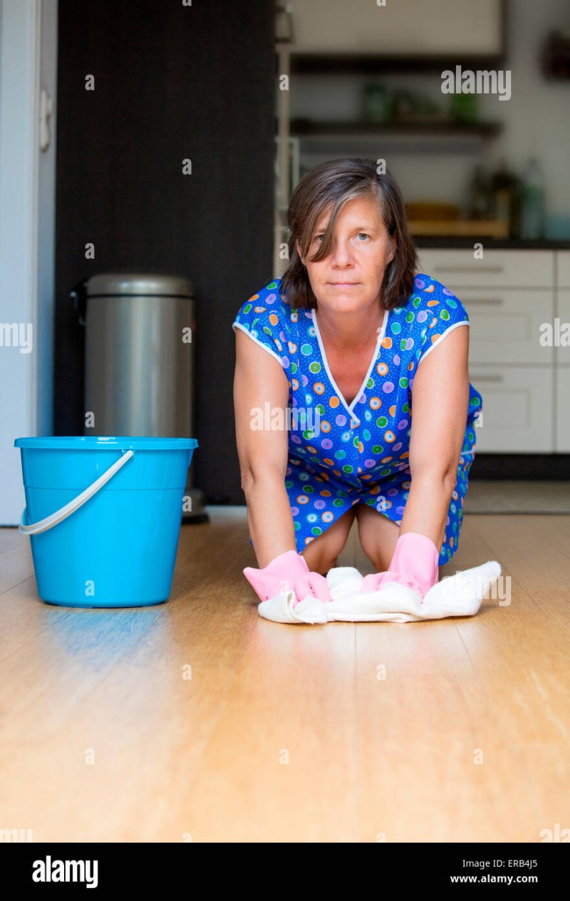 An elderly woman washes the floor